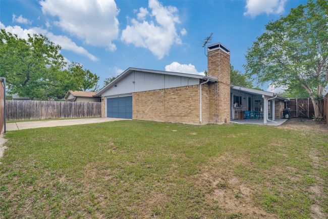 View of home's exterior with brick siding, a fenced backyard, concrete driveway, an attached garage, and a chimney | Image 24