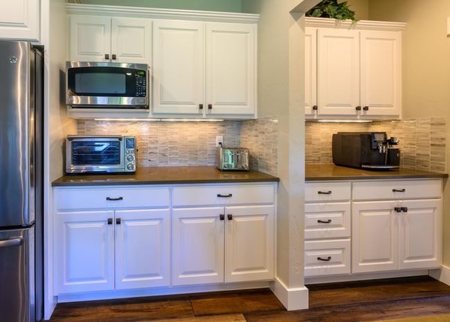 Kitchen with stainless steel appliances, dark countertops, white cabinetry, dark wood-style flooring, and tasteful backsplash | Image 15