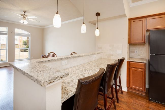 Kitchen featuring backsplash, freestanding refrigerator, dark wood-type flooring, and brown cabinets | Image 7