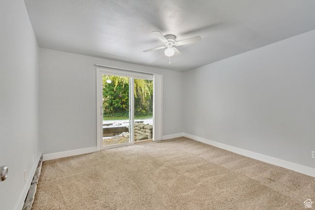 Empty room with a ceiling fan, carpet flooring, baseboard heating, and baseboards | Image 8
