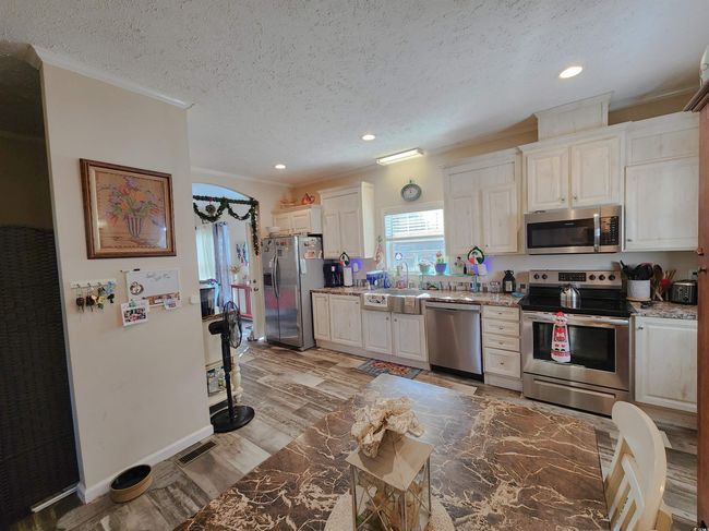 Kitchen featuring sink, light hardwood / wood-style flooring, ornamental molding, a textured ceiling, and appliances with stainless steel finishes | Image 11