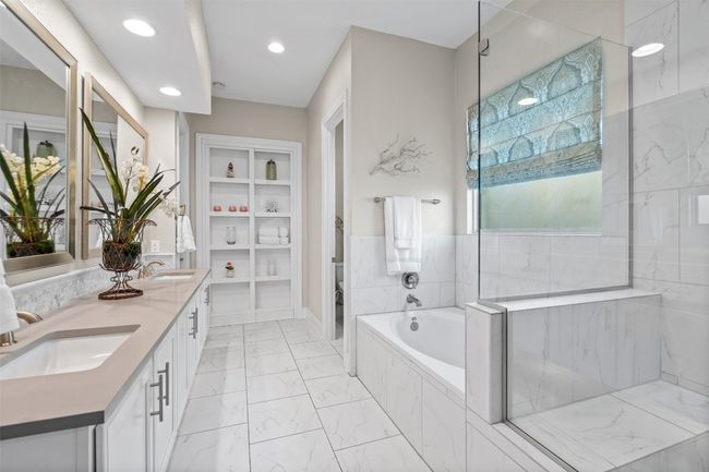 The spa-inspired primary bathroom offers a luxurious escape, complete with double vanities, a large soaking tub, a walk-in shower with designer tile, and elegant finishes throughout. | Image 18