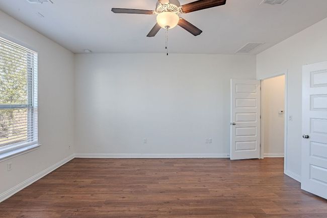 Empty room with baseboards, visible vents, dark wood-type flooring, and a ceiling fan | Image 14