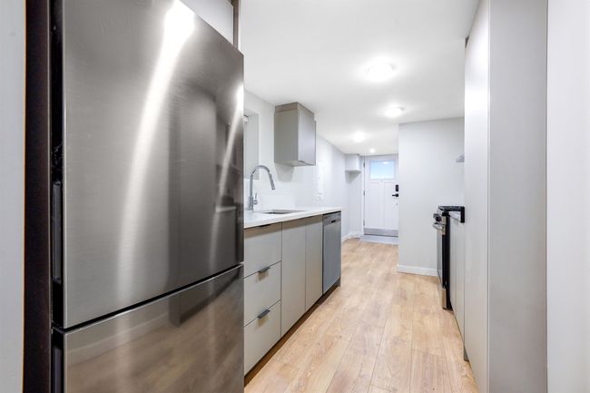 Kitchen with gray cabinetry, a sink, appliances with stainless steel finishes, light wood finished floors, and light countertops | Image 4