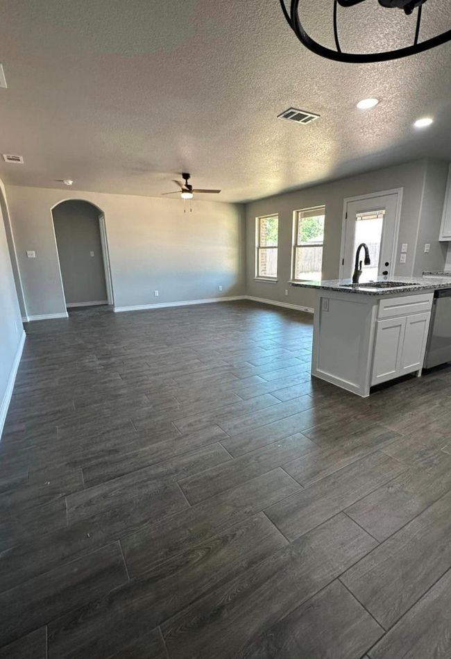 Kitchen featuring stainless steel dishwasher, ceiling fan, open floor plan, wood finish floors, and a textured ceiling | Image 5