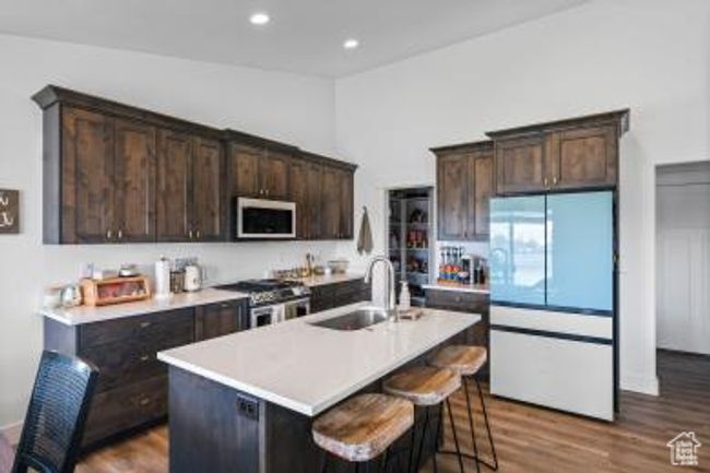 Kitchen featuring dark brown cabinets, dark wood-style floors, a sink, and appliances with stainless steel finishes | Image 11