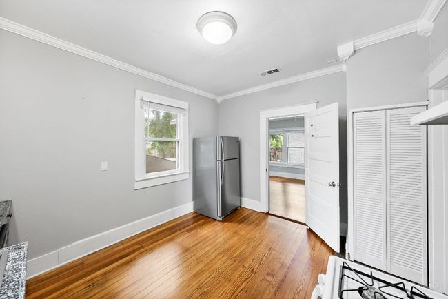 Unfurnished bedroom with freestanding refrigerator, ornamental molding, light wood finished floors, multiple windows, and baseboards | Image 10