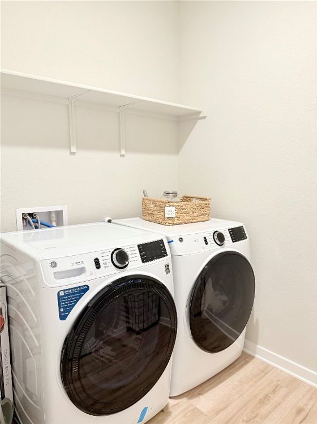 Washroom featuring laundry area, washer and clothes dryer, light wood-style flooring, and baseboards | Image 27