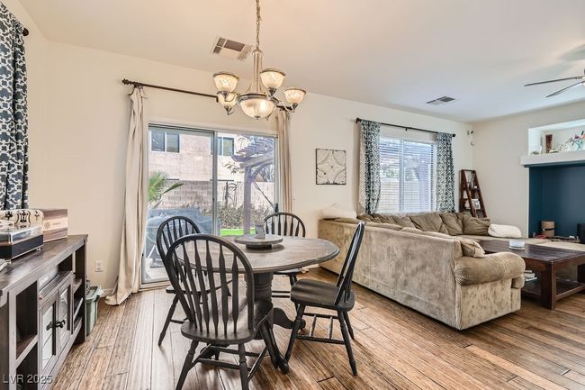 Dining room featuring ceiling fan with notable chandelier, visible vents, and wood finished floors | Image 11