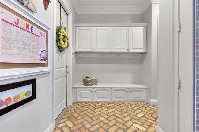 Convenient drop zone just off the 3-car garage featuring built-in hooks and cabinets, perfect for backpacks and shoes. Charming patterned old brick flooring adds character and durability. | Image 40