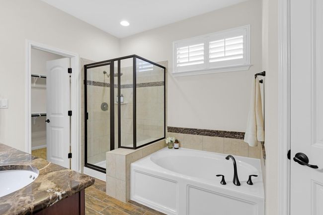 En-suite full bath with a spacious closet, a garden tub, recessed lighting, a stall shower and walk in closet | Image 16