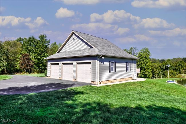 View of side of home with a garage, roof with shingles, and a lawn | Image 12