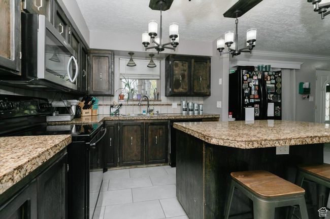 Kitchen with a chandelier, a sink, black appliances, and a textured ceiling | Image 12