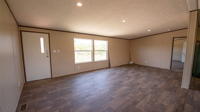 Empty room with dark wood-style flooring, a textured ceiling, crown molding, and recessed lighting | Image 14