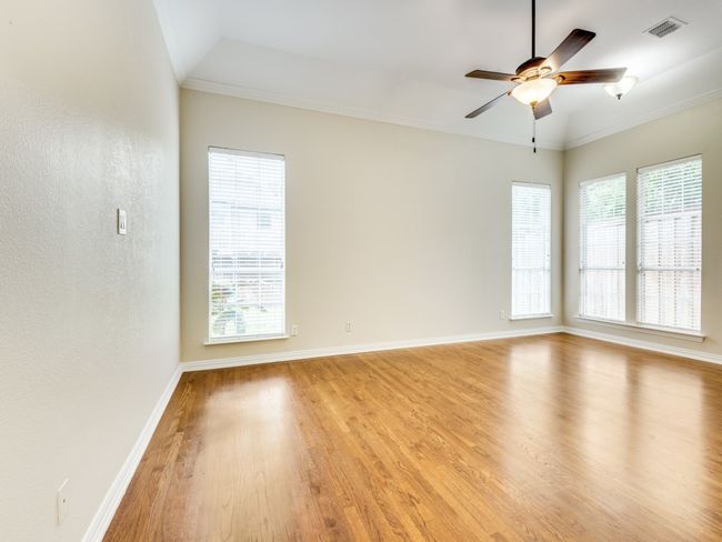 Roomy primary bedroom featuring hardwood floors, ceiling fan, plenty of natural light, and crown molding. A king bed will fit nicely and still have room for additional furniture. | Image 16