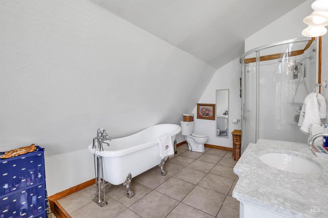 Full bath with vaulted ceiling, a shower stall, a freestanding tub, vanity, and tile patterned flooring | Image 24