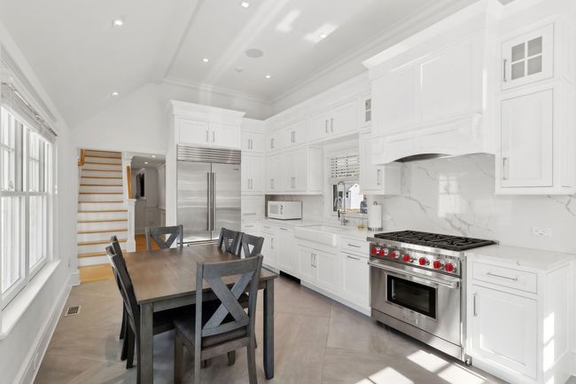 Kitchen with white cabinets, a healthy amount of sunlight, high end appliances, and vaulted ceiling | Image 24