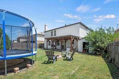 Back of property featuring a patio, a pergola, a trampoline, and a yard | Image 2