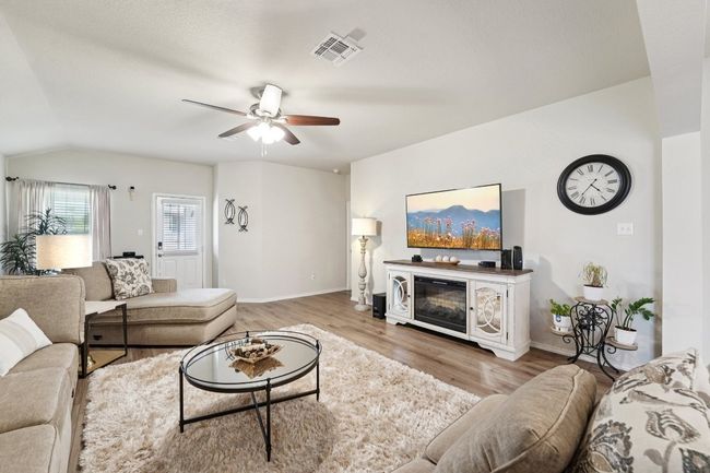 Living area with a ceiling fan, light wood-type flooring, vaulted ceiling, and a glass covered fireplace | Image 6