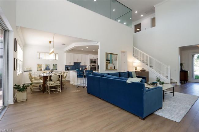 Living area with a towering ceiling, stairs, and light wood-style flooring | Image 4