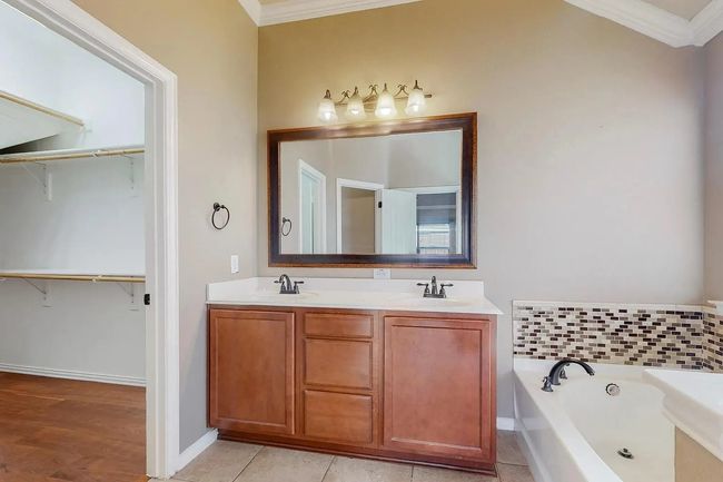 Bathroom with ornamental molding, a bath, double vanity, and a walk in closet | Image 12