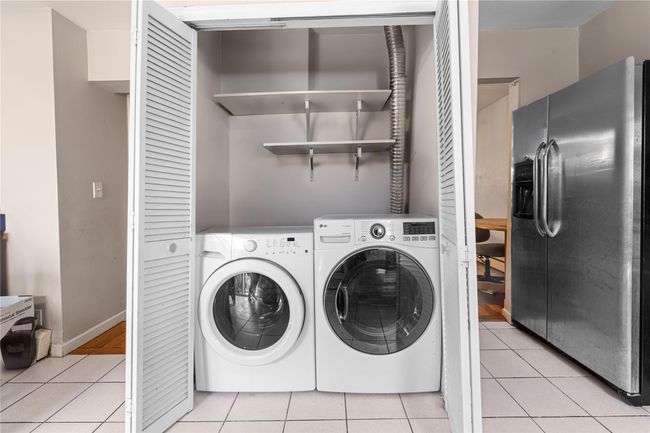 Laundry room with light tile patterned floors and washing machine and clothes dryer | Image 6