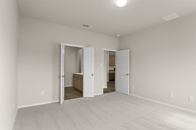 Unfurnished bedroom featuring carpet flooring, baseboards, ensuite bathroom, and visible vents | Image 17