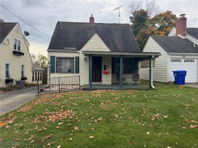 View of front facade featuring a front yard, a garage, and a porch | Image 1