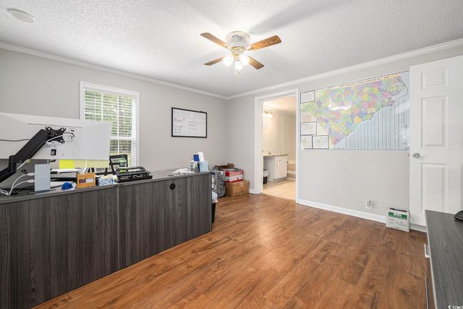 Office space with ornamental molding, a ceiling fan, wood finished floors, and a textured ceiling | Image 16