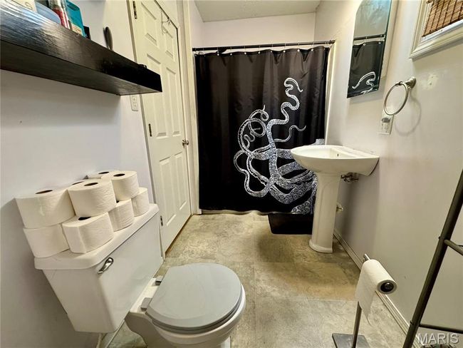 Bathroom featuring stone finish flooring, toilet, baseboards, and a shower with curtain | Image 6
