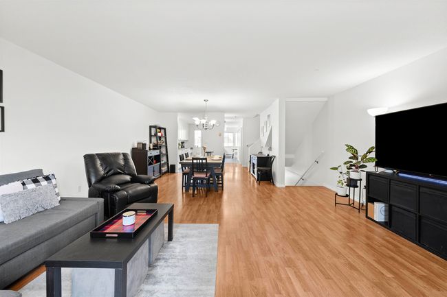 Living room with light wood-style flooring, an inviting chandelier, and baseboards | Image 16