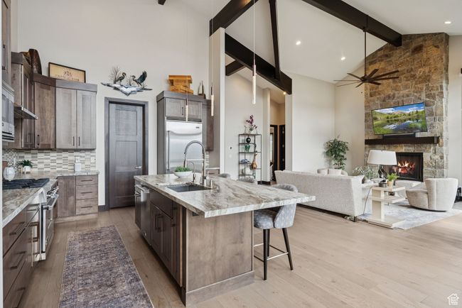 Kitchen featuring high quality appliances, high vaulted ceiling, beamed ceiling, open floor plan, and a breakfast bar | Image 20