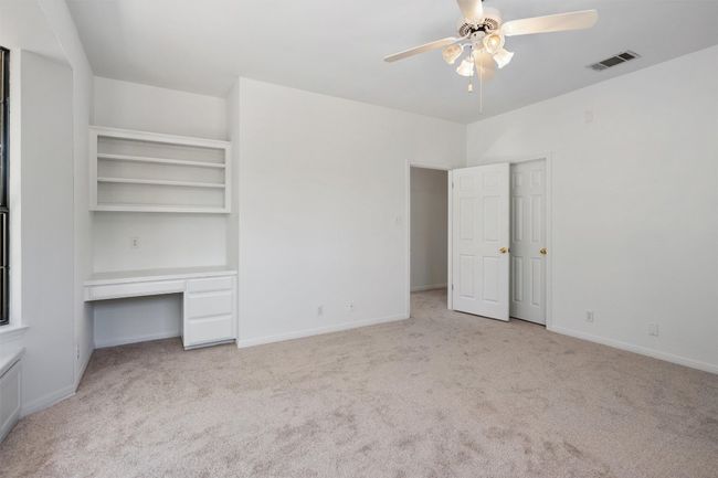 Unfurnished bedroom with built in study area, baseboards, visible vents, and carpet | Image 30