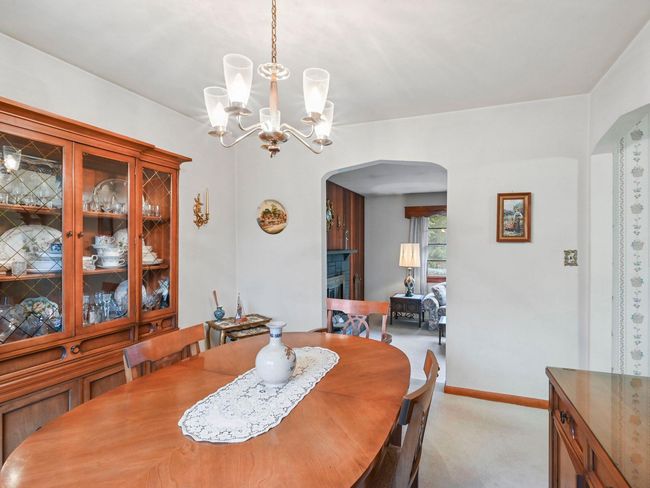 Dining space featuring a stone fireplace, light colored carpet, and a notable chandelier | Image 20