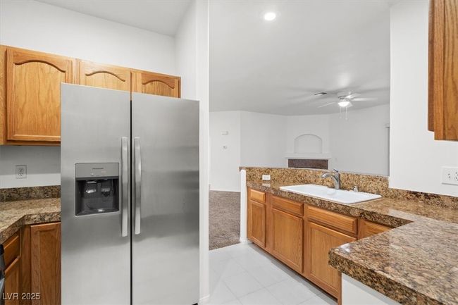 Kitchen with a ceiling fan, a peninsula, a sink, dark countertops, and stainless steel fridge | Image 6