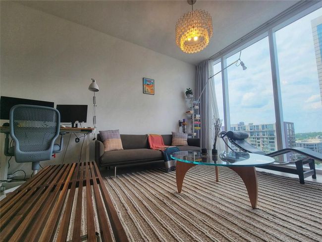 Carpeted living room with floor to ceiling windows and a chandelier | Image 22