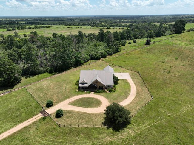 Aerial front view of a charming countryside home a welcoming circular driveway, 3 car garage and pool. | Image 48