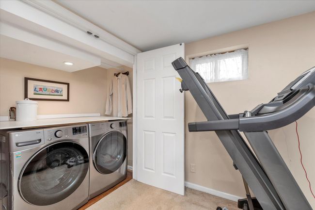 Clothes washing area featuring baseboards, laundry area, washer and dryer, and light colored carpet | Image 13