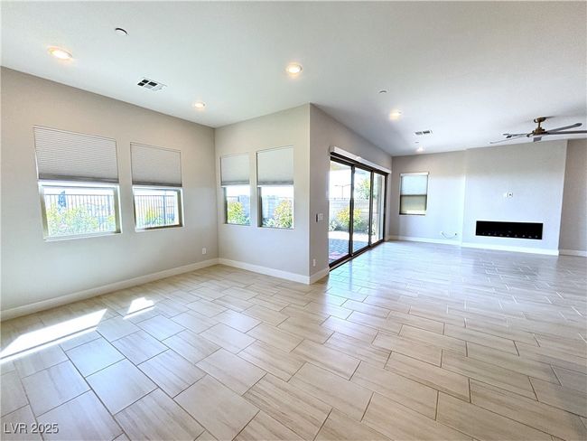 Unfurnished living room featuring a wealth of natural light, visible vents, a ceiling fan, and baseboards | Image 8