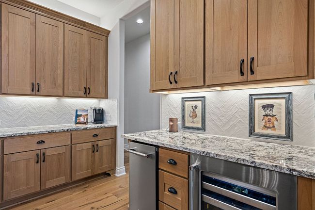 Kitchen with light stone counters, light wood-type flooring, beverage cooler, and backsplash | Image 15