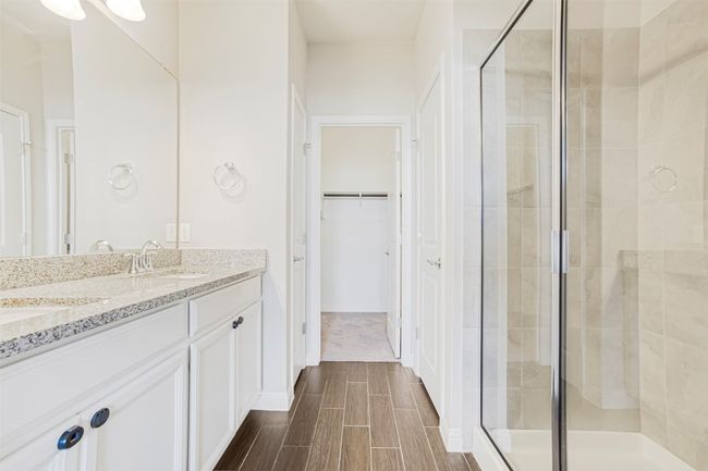 Full bathroom featuring a shower stall, wood tiled floors, double vanity, and a spacious closet | Image 20