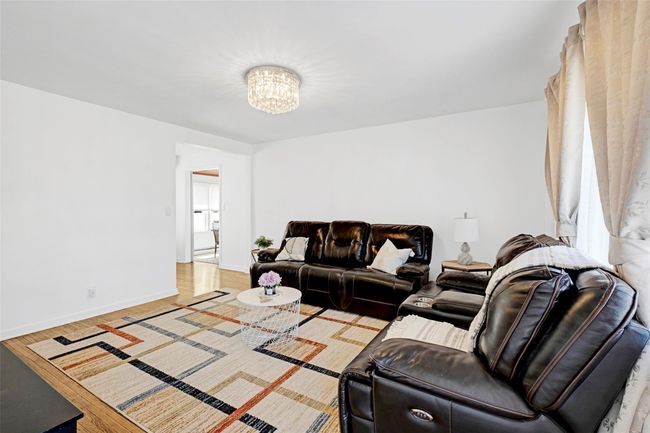Living area with a chandelier, wood finished floors, and baseboards | Image 4