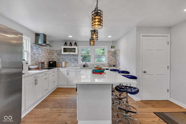 Gourmet cooks kitchen with abundant below cabinet thoughtful storage, counter height center island, access to powder room, rear entrance/exit, and main floor office/bedrooms. | Image 11