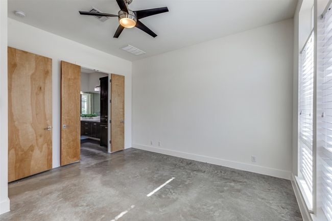 Unfurnished bedroom with a ceiling fan, concrete floors, visible vents, and baseboards | Image 15