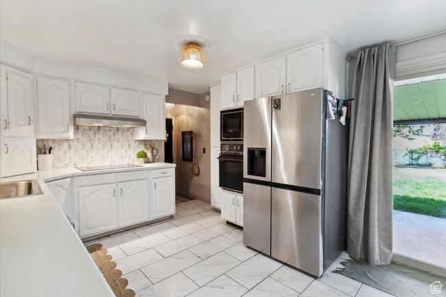 Kitchen featuring black appliances, under cabinet range hood, white cabinets, and light countertops | Image 8