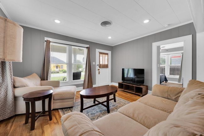 Living room with crown molding, plenty of natural light, wood finished floors, a ceiling fan, and baseboards | Image 17
