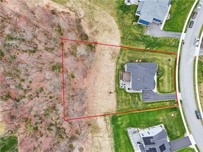 Aerial view of a beautifully maintained two-story home set on a spacious lot with expansive green lawn and private wooded backdrop. Located on a quiet cul-de-sac, this property offers scenic views, a paved driveway, and excellent curb appeal. | Image 39