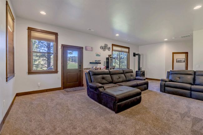 Carpeted living room featuring recessed lighting, baseboards, and a wood stove | Image 32