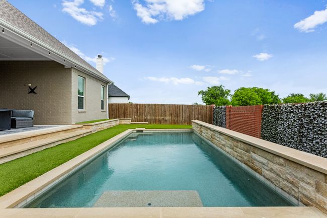 Beautiful pool with narrow tanning ledge making room for a swimming lane. 3 waterfalls on the right side | Image 36