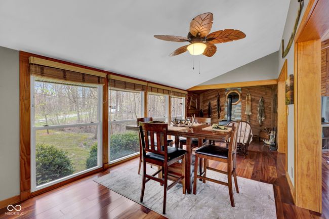 dining room featuring ceiling fan, vaulted ceiling, a wood stove, and Brazilian Cherry finished floors | Image 10